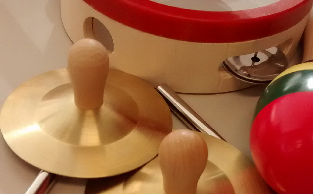 Musical instruments lie jumbled on the table: Cymbals, maracas, and a tambourine lie on top of a triangle.